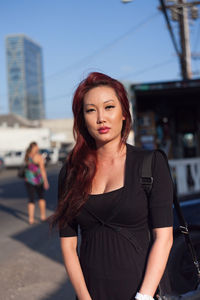 Beautiful young woman standing against sky in city