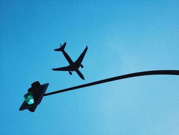 Low angle view of silhouette birds flying against clear blue sky