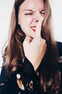 Portrait of beautiful young woman making face against wall