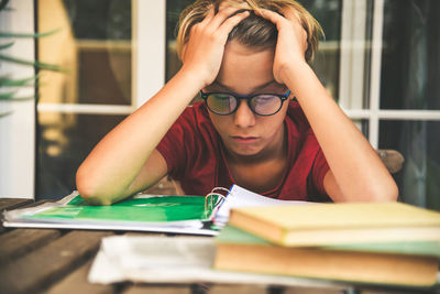 Tired student doing homework at home sitting outdoor with school books and newspaper. boy weary