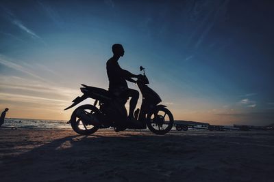 Silhouette of man riding bicycle on beach