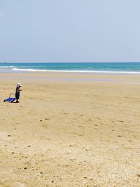 Mid distance view of boy standing at beach against clear sky