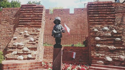 Statue against brick wall