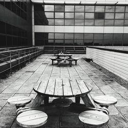 Empty wooden benches with seats on footpath against modern building