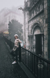 Full length of woman standing by railing in winter