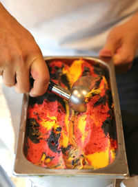 Cropped hand of person removing ice cream from container with serving scoop