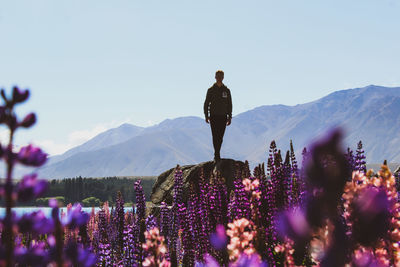 Man standing on rock against sky