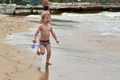 Full length of shirtless boy on beach