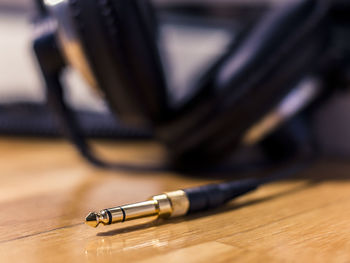 Black hi-fi headphones with a gold input jack on a wooden floor