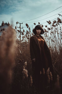 Portrait of woman standing on field against sky