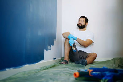 Home renovation. caucasian bearded man having rest after painting wall