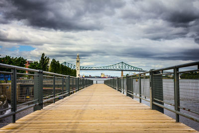 View of footbridge over bridge against cloudy sky