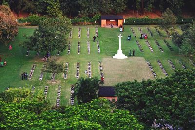 High angle view of people and white cross on field in cemetery