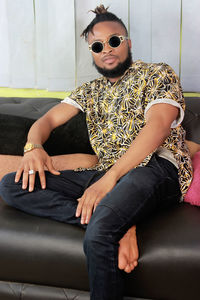 Portrait of young man wearing sunglasses sitting on sofa