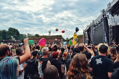 Group of people enjoying at music concert against sky