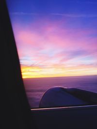 Close-up of airplane wing against sky during sunset