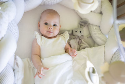 High angle view of cute baby girl lying on bed