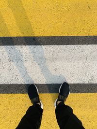 Low section of man standing on yellow road