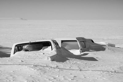 Snow covered cars on land against sky