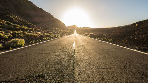 Road amidst mountains against sky during sunset