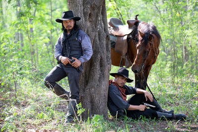 Friends with horse by tree in forest