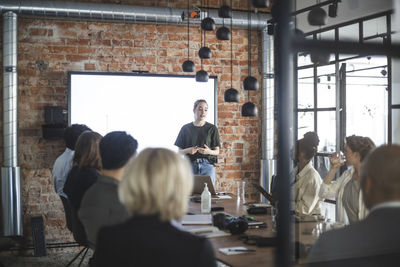 Young businesswoman giving presentation to colleagues during meeting at office