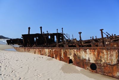 Abandoned built structure on land against clear blue sky
