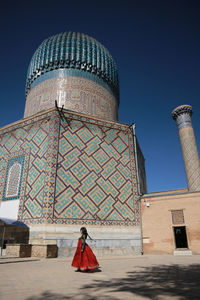 Woman walking by building against sky