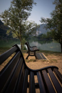 Empty bench in park against sky