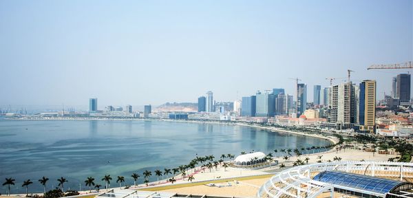 View of cityscape by river against clear sky