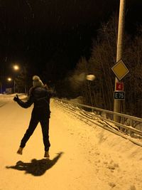 Full length of man walking on snow covered road at night