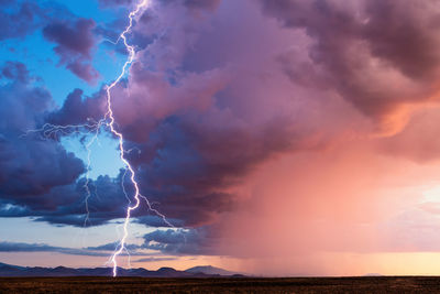 A powerful lightning bolt strikes from a storm at sunset near flagstaff, arizona