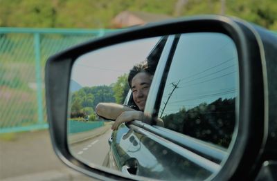 Reflection of teenage boy seen in side-view mirror