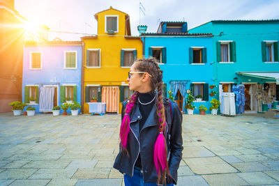 Portrait of young woman standing against building