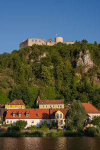 Buildings by trees against clear sky