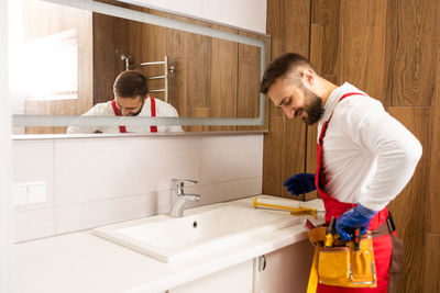 Side view of man washing hands in bathroom