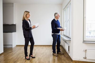 Mature real estate agents looking through window at home