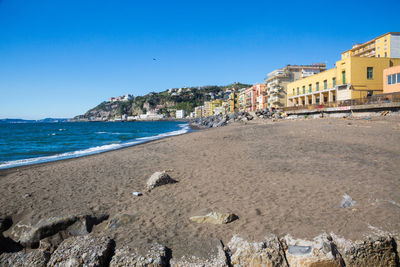 View of sea and buildings against clear blue sky