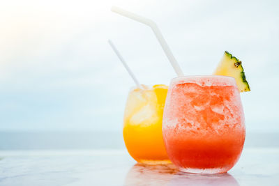 Close-up of drinks on table against sea