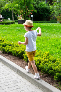 Rear view of boy running on footpath