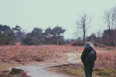 Rear view of man walking on road against sky