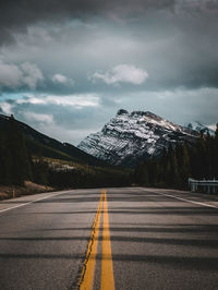 Empty road by mountain against sky