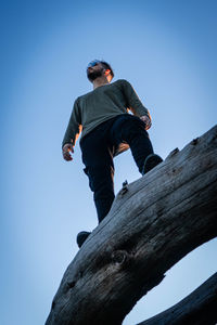 Low angle view of man on rock against blue sky