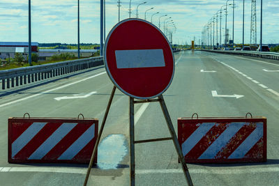 Arrow sign on road against sky