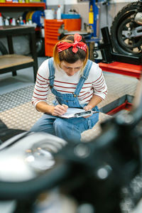 Mechanic reviewing documentation of motorcycle on garage