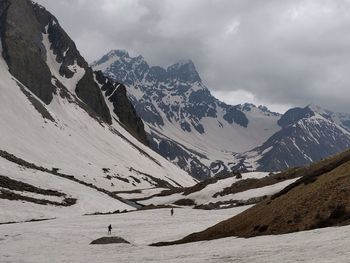 People walking on snow covered land against mountain range