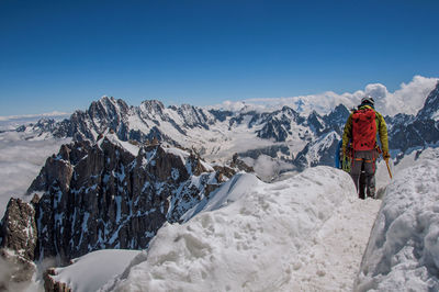 Climbers walking on snowy path in a sunny day at the aiguille du midi, near chamonix, france.