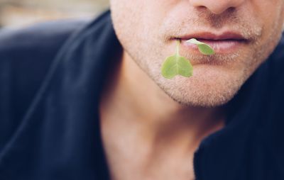 Midsection of man carrying herb in mouth