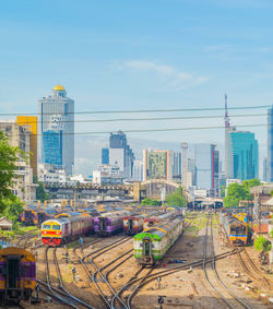 Train on railroad tracks by buildings in city against sky