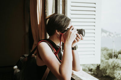 Young woman photographing camera at home